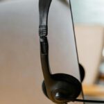 delle cuffie con microfono sono appoggiate su un lap top su un tavolo di legno