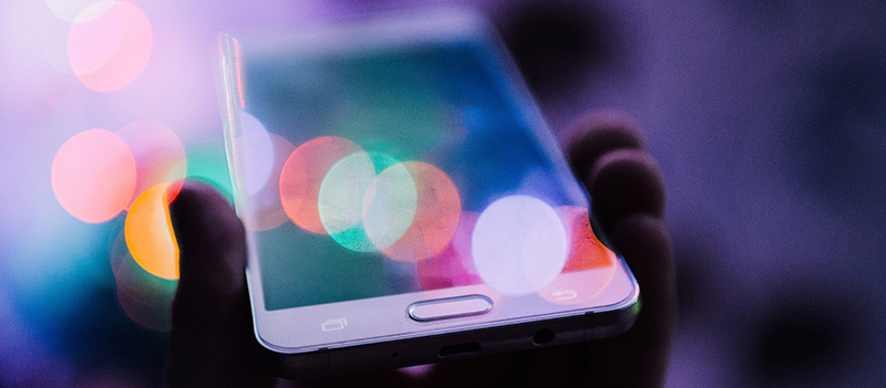 Una mano regge uno smartphone che riflette la luce