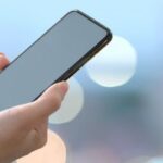Una donna tiene in mano uno smartphone spento