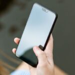 Una donna tiene in mano uno smartphone spento