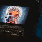 Uno smarphone inquadra un laptop acceso sul quale c'è una grafica 3D di un uomo