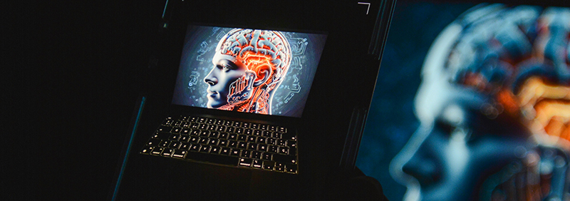 Uno smarphone inquadra un laptop acceso sul quale c'è una grafica 3D di un uomo